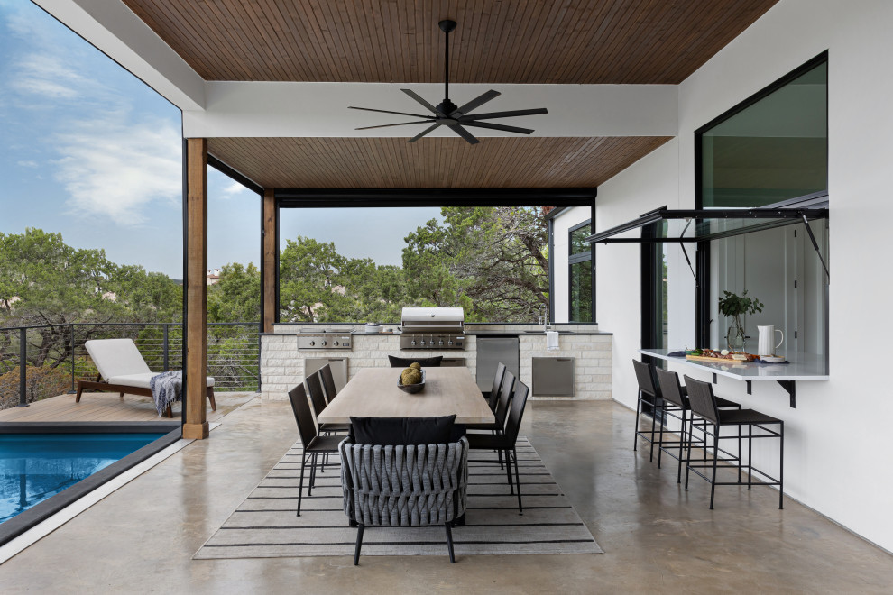 This is an example of a large scandi back patio in Austin with an outdoor kitchen and a roof extension.