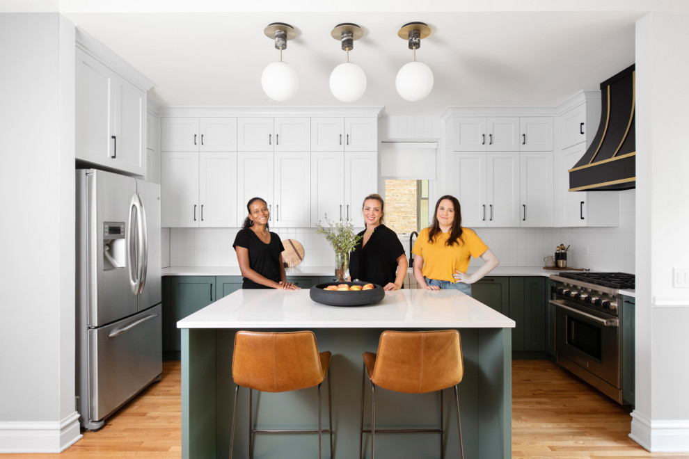 Example of a mid-sized classic u-shaped medium tone wood floor and brown floor eat-in kitchen design in Chicago with a drop-in sink, shaker cabinets, green cabinets, quartz countertops, white backsplash, ceramic backsplash, stainless steel appliances, an island and white countertops