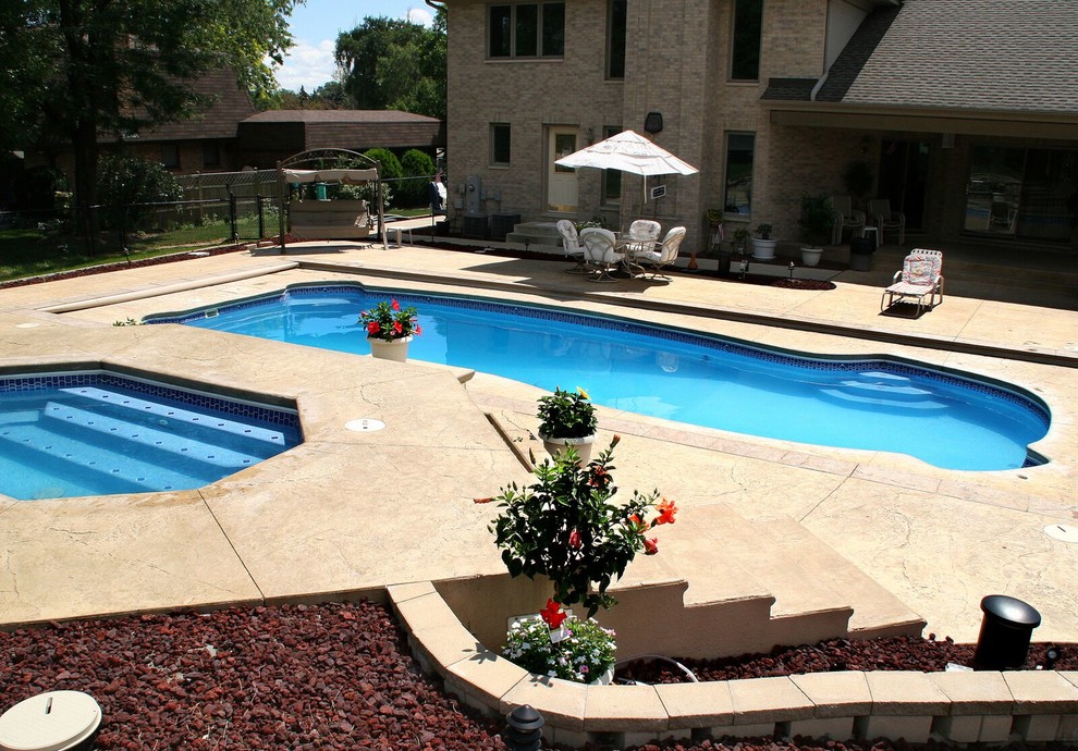 Design ideas for a large traditional backyard custom-shaped pool in Chicago with a hot tub and stamped concrete.