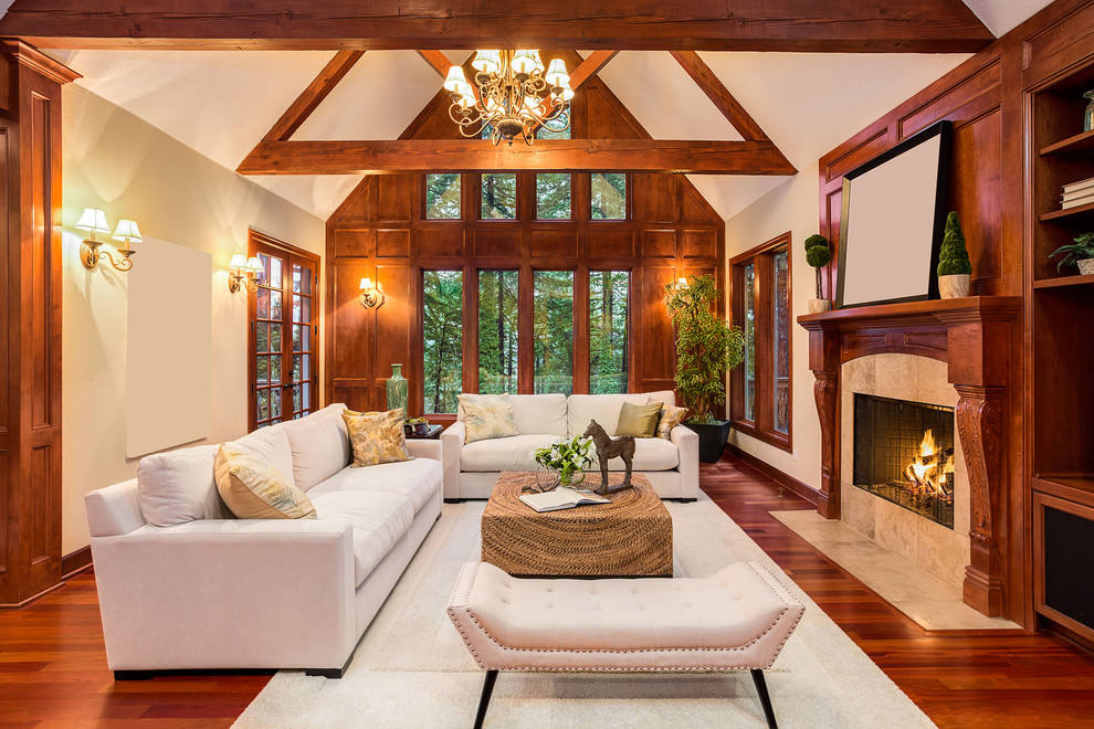 Photo of a large traditional open concept family room in Seattle with a library, beige walls, medium hardwood floors, a standard fireplace, a stone fireplace surround and a wall-mounted tv.