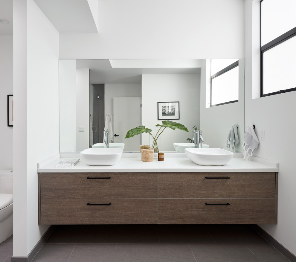 Example of a mid-sized trendy master porcelain tile, gray floor and double-sink toilet room design in Los Angeles with flat-panel cabinets, medium tone wood cabinets, a one-piece toilet, white walls, a vessel sink, quartz countertops, white countertops and a floating vanity