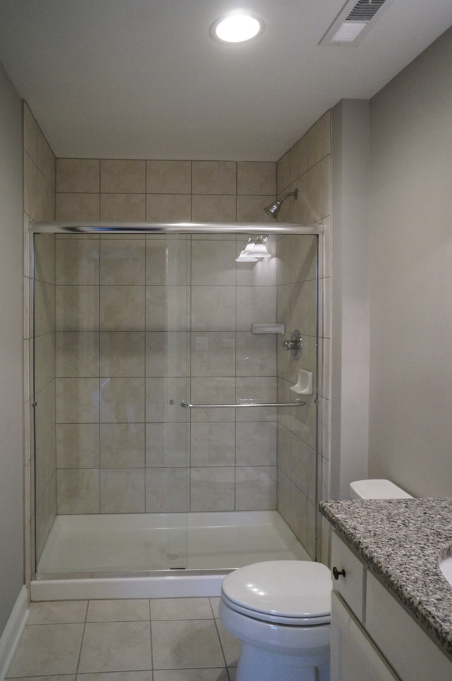 Photo of a mid-sized beach style bathroom in Chicago with white cabinets, granite benchtops, gray tile, ceramic tile, grey walls and ceramic floors.