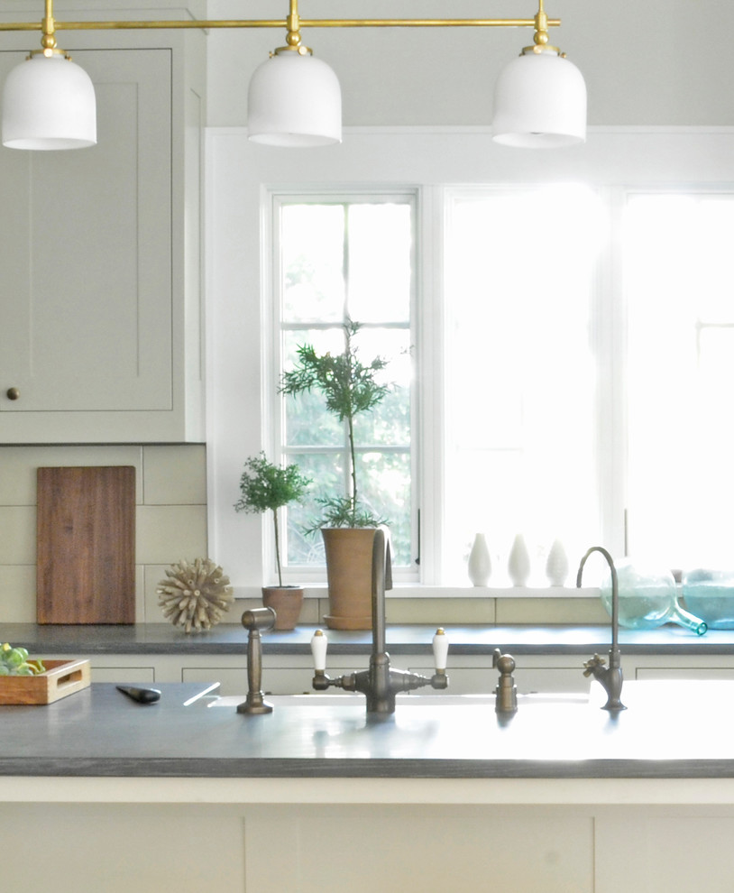 Example of a transitional l-shaped eat-in kitchen design in New York with a farmhouse sink, shaker cabinets, gray cabinets, limestone countertops, beige backsplash, subway tile backsplash and stainless steel appliances
