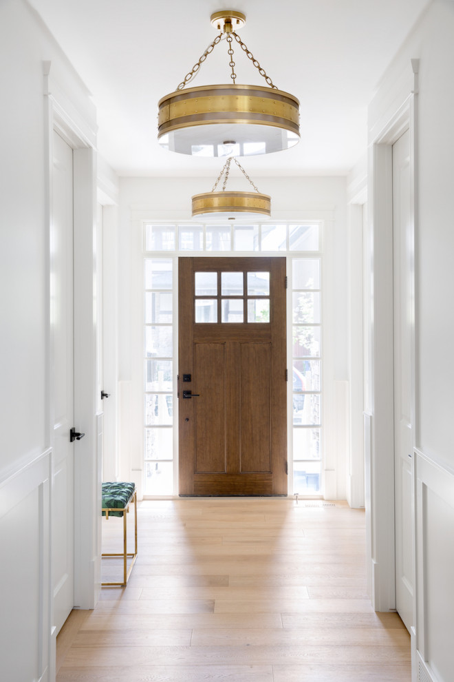 Источник вдохновения для домашнего уюта: фойе в стиле неоклассика (современная классика) с белыми стенами, светлым паркетным полом, одностворчатой входной дверью, входной дверью из темного дерева, белым полом и панелями на стенах