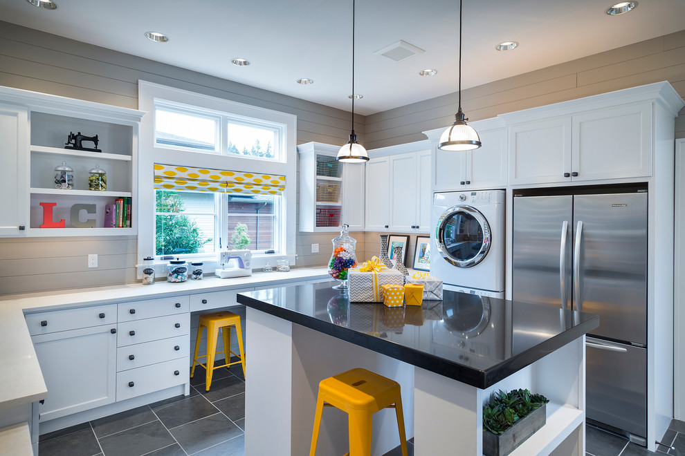 Inspiration for a transitional laundry room in Portland with white cabinets, grey floor, black benchtop and a stacked washer and dryer.