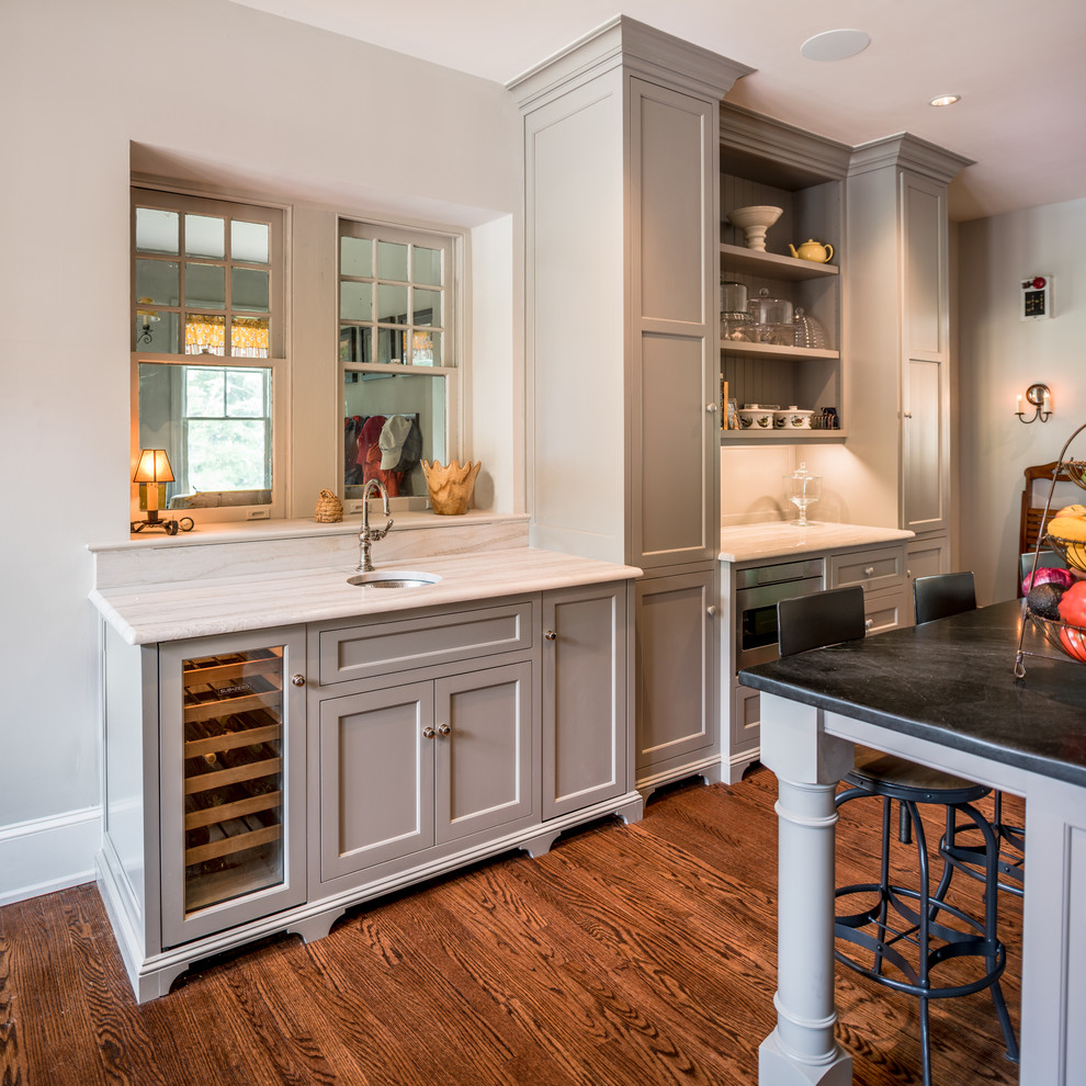 Inspiration for a country single-wall wet bar in Philadelphia with an undermount sink, shaker cabinets, grey cabinets, marble benchtops, medium hardwood floors, brown floor and white benchtop.