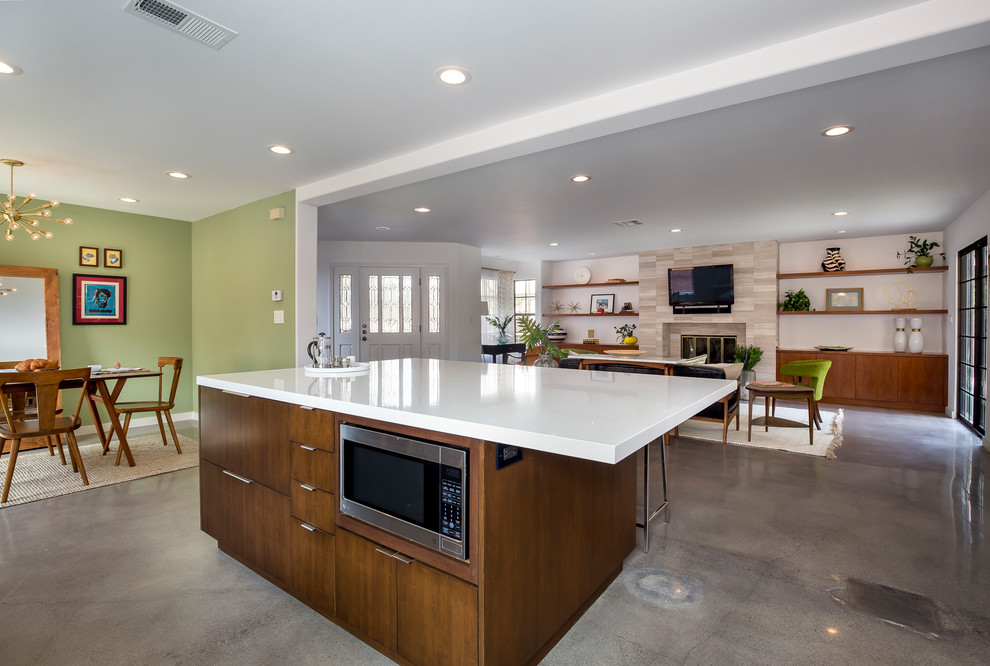 This is an example of a large midcentury single-wall open plan kitchen in Los Angeles with an undermount sink, flat-panel cabinets, dark wood cabinets, quartz benchtops, white splashback, stainless steel appliances, concrete floors, with island, ceramic splashback and grey floor.