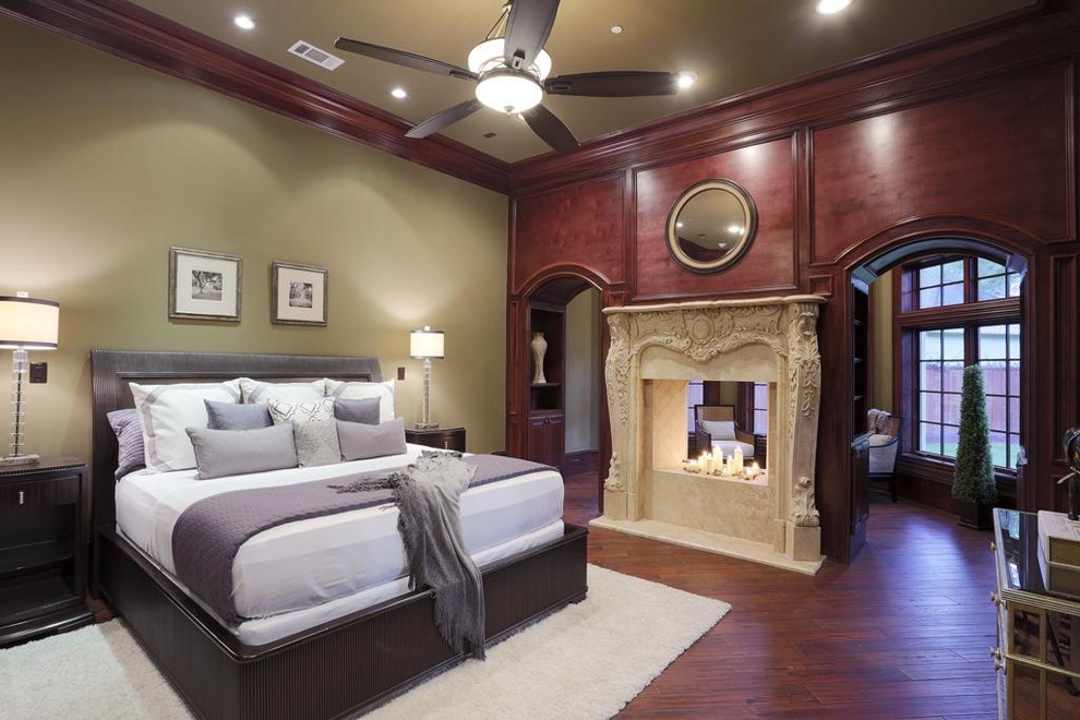 Design ideas for a large traditional master bedroom in Houston with beige walls, medium hardwood floors, a two-sided fireplace and a stone fireplace surround.