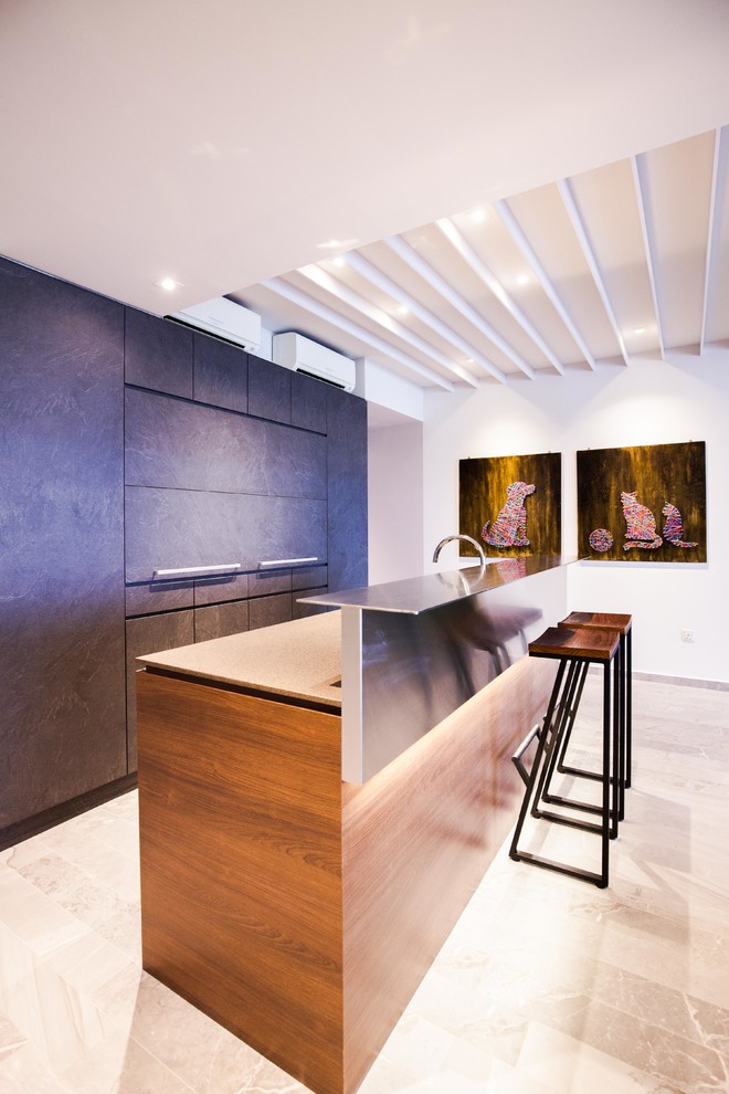 This is an example of a contemporary galley open plan kitchen in Singapore with flat-panel cabinets, stainless steel benchtops and with island.