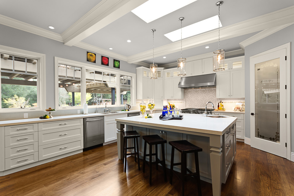 This is an example of a traditional l-shaped kitchen in San Francisco with an undermount sink, shaker cabinets, white cabinets, stainless steel appliances, dark hardwood floors and with island.