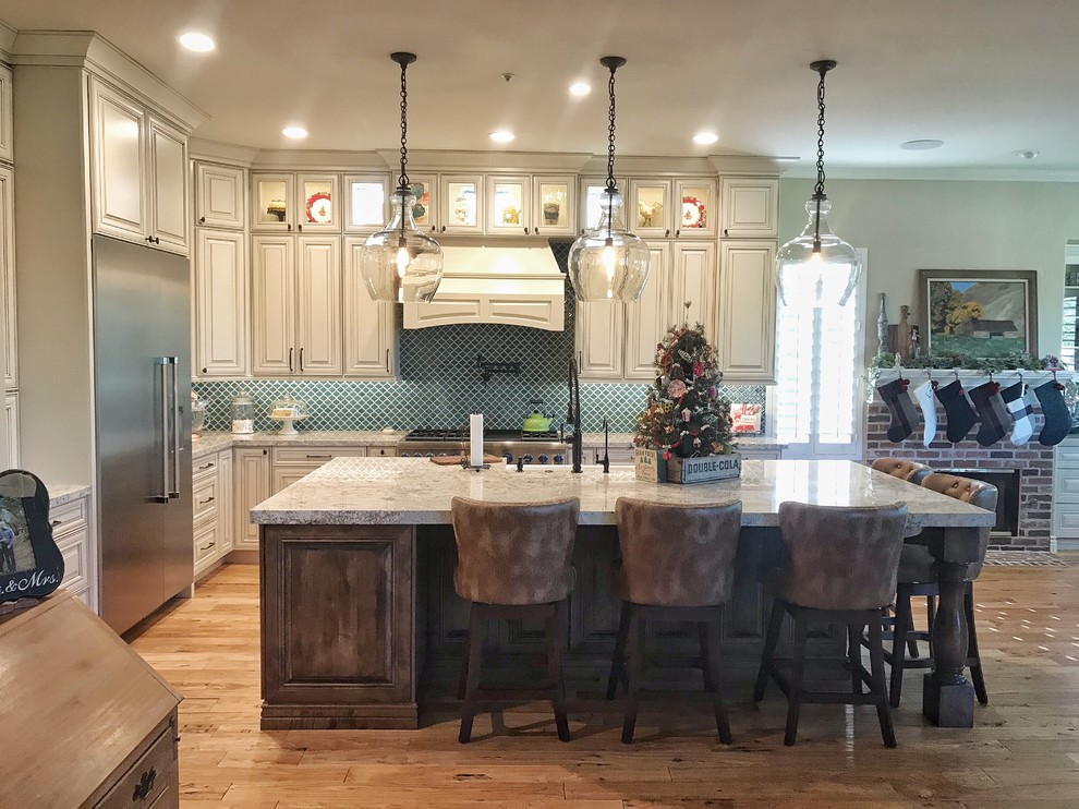 Inspiration for a large transitional l-shaped eat-in kitchen in Phoenix with a farmhouse sink, raised-panel cabinets, white cabinets, granite benchtops, blue splashback, glass sheet splashback, stainless steel appliances, light hardwood floors, with island, brown floor and beige benchtop.