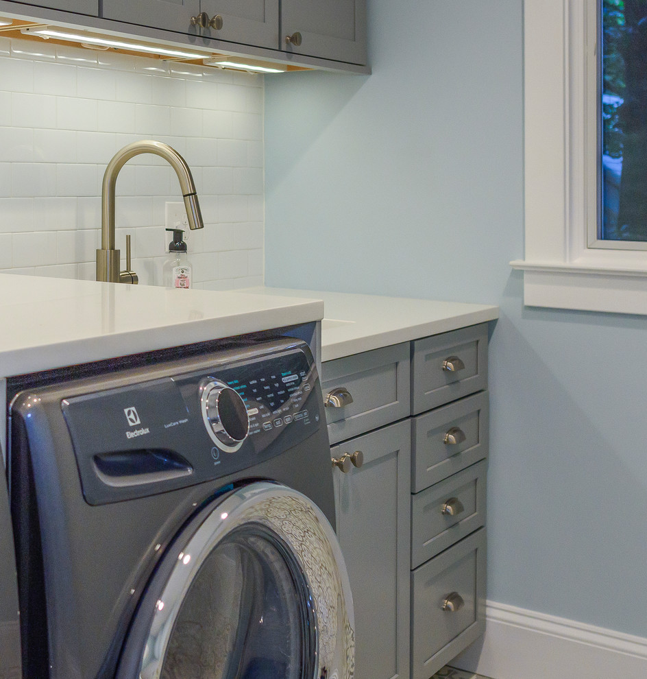 Photo of a mid-sized transitional single-wall dedicated laundry room in DC Metro with an undermount sink, shaker cabinets, grey cabinets, quartz benchtops, blue walls, a side-by-side washer and dryer and multi-coloured floor.