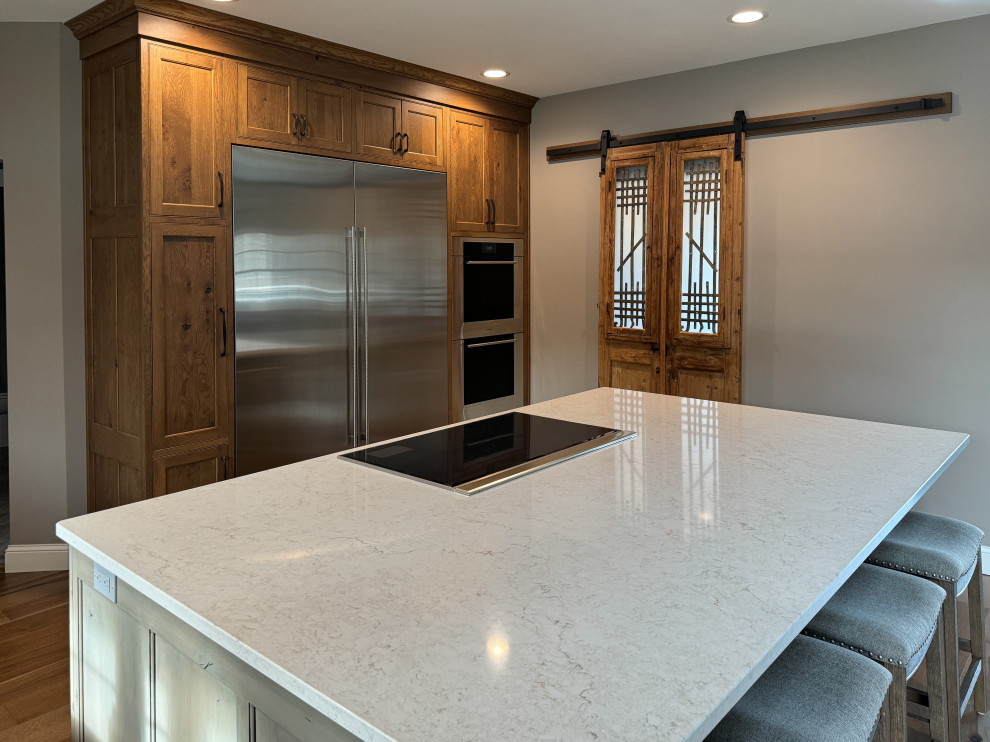 Example of a large transitional l-shaped light wood floor eat-in kitchen design with beaded inset cabinets, quartz countertops, stainless steel appliances and an island