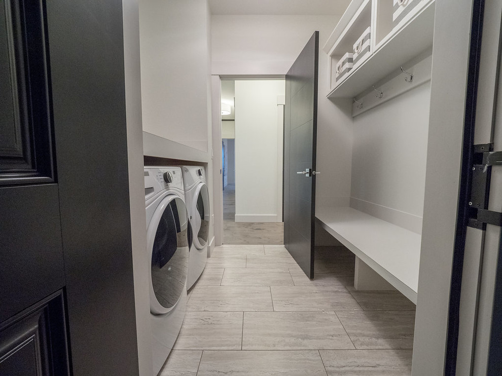 This is an example of a mid-sized modern single-wall utility room in Edmonton with open cabinets, laminate benchtops, white walls, vinyl floors, a side-by-side washer and dryer and grey floor.