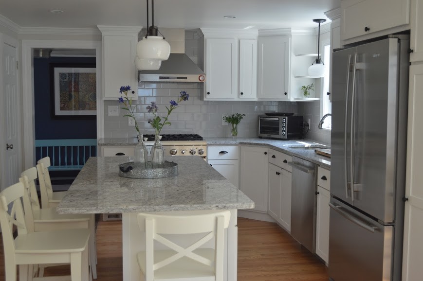 Enclosed kitchen - mid-sized transitional l-shaped medium tone wood floor enclosed kitchen idea in Boston with an undermount sink, shaker cabinets, white cabinets, granite countertops, gray backsplash, subway tile backsplash, stainless steel appliances and an island