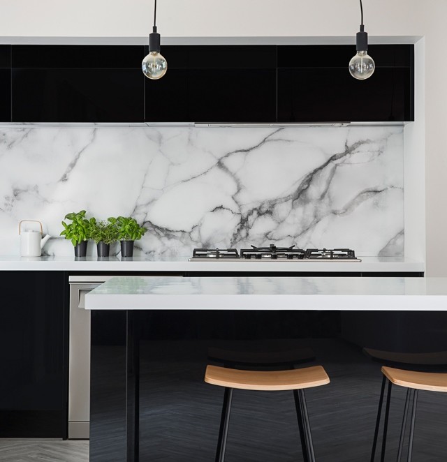 Mid-sized modern l-shaped open plan kitchen in Christchurch with a double-bowl sink, flat-panel cabinets, black cabinets, white splashback, marble splashback, stainless steel appliances, vinyl floors, with island, grey floor and white benchtop.