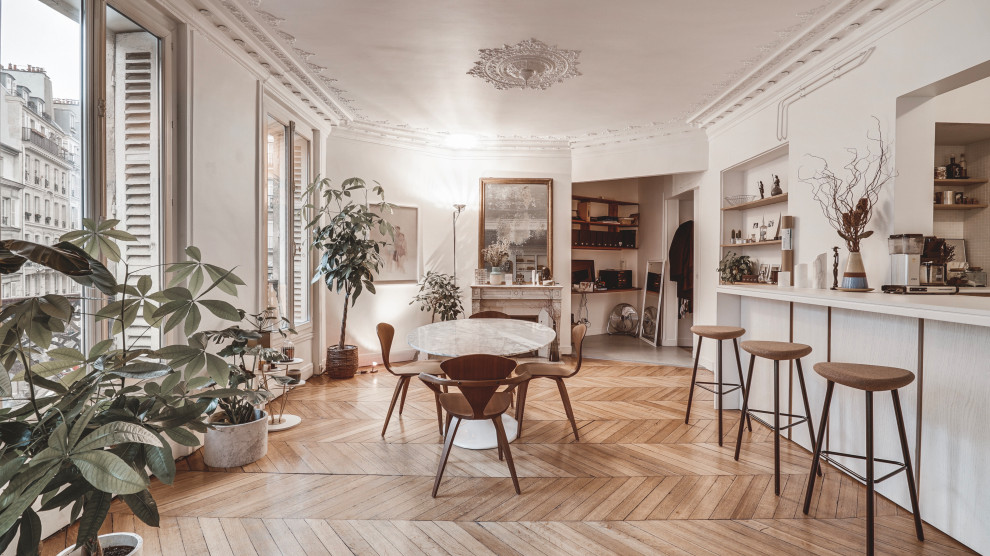 Design ideas for an expansive scandinavian open plan dining in Paris with white walls, medium hardwood floors, a standard fireplace, a stone fireplace surround, brown floor and decorative wall panelling.