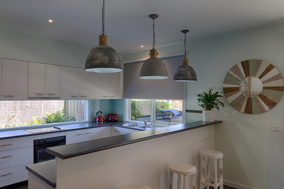 Inspiration for a small modern open plan kitchen in Melbourne with a double-bowl sink, white cabinets, laminate benchtops, blue splashback, glass sheet splashback, black appliances, ceramic floors and no island.