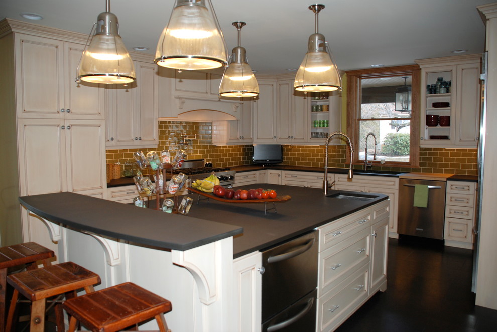 Inspiration for a mid-sized transitional u-shaped cork floor kitchen remodel with recessed-panel cabinets, distressed cabinets, solid surface countertops, green backsplash, glass tile backsplash, stainless steel appliances and an island