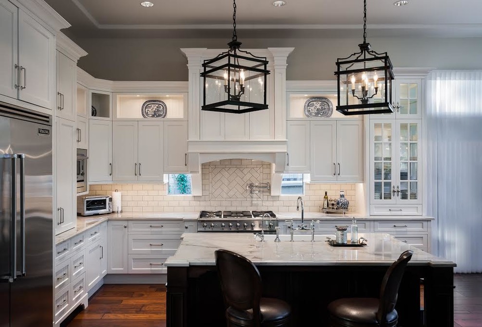 Photo of a mid-sized traditional u-shaped eat-in kitchen in Phoenix with a single-bowl sink, raised-panel cabinets, white cabinets, granite benchtops, white splashback, subway tile splashback, stainless steel appliances, dark hardwood floors and with island.
