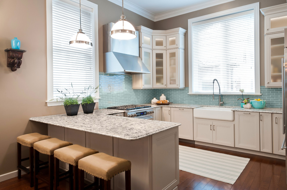Inspiration for a mid-sized transitional u-shaped eat-in kitchen in St Louis with a farmhouse sink, recessed-panel cabinets, granite benchtops, blue splashback, stainless steel appliances, white cabinets, subway tile splashback, dark hardwood floors and a peninsula.