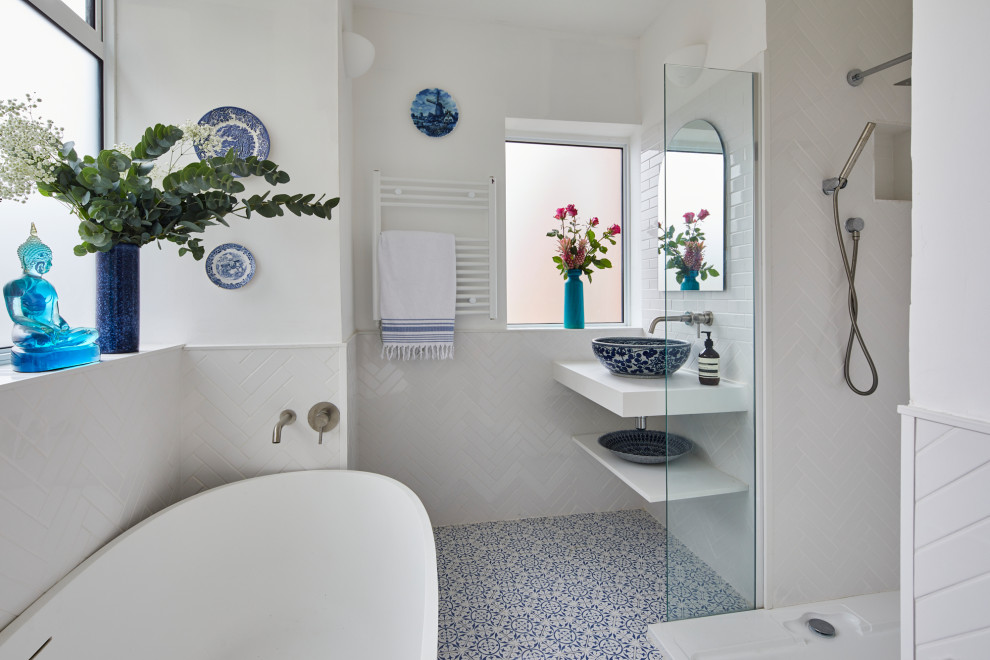 Design ideas for a mid-sized contemporary master bathroom in London with open cabinets, white cabinets, a freestanding tub, an alcove shower, white tile, ceramic tile, white walls, mosaic tile floors, a vessel sink, blue floor and white benchtops.