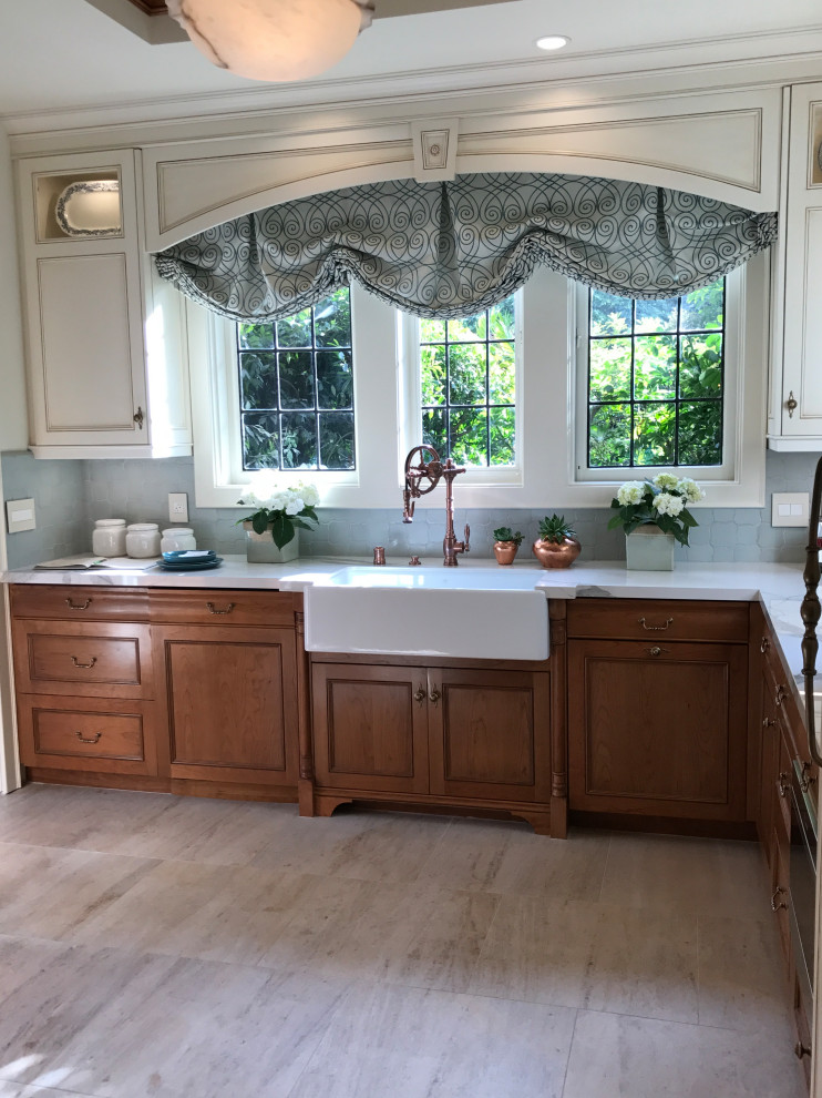 Mid-sized elegant galley porcelain tile, beige floor and coffered ceiling dedicated laundry room photo in Los Angeles with a farmhouse sink, recessed-panel cabinets, light wood cabinets, blue backsplash, ceramic backsplash and white walls