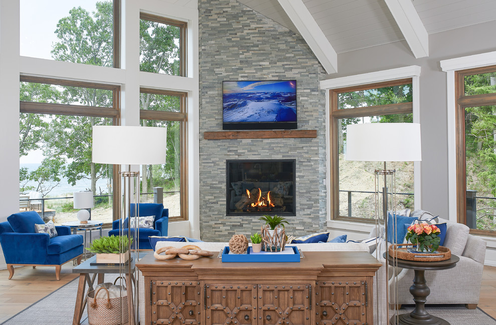 Design ideas for a beach style open concept family room in Grand Rapids with light hardwood floors, a corner fireplace, grey walls and a stone fireplace surround.