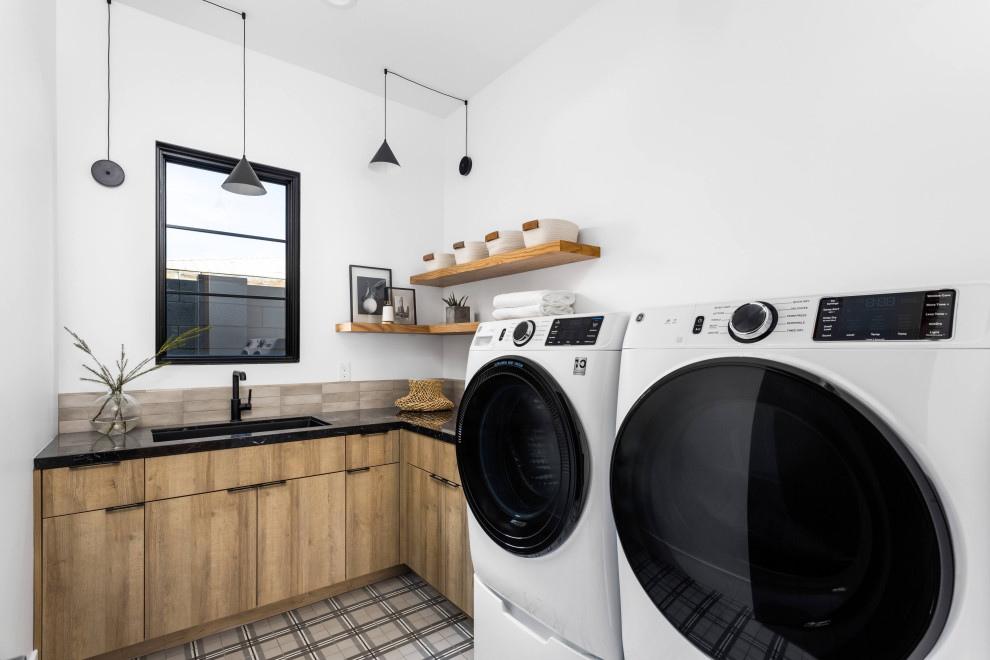 Modern laundry room in Phoenix with white walls and black benchtop.