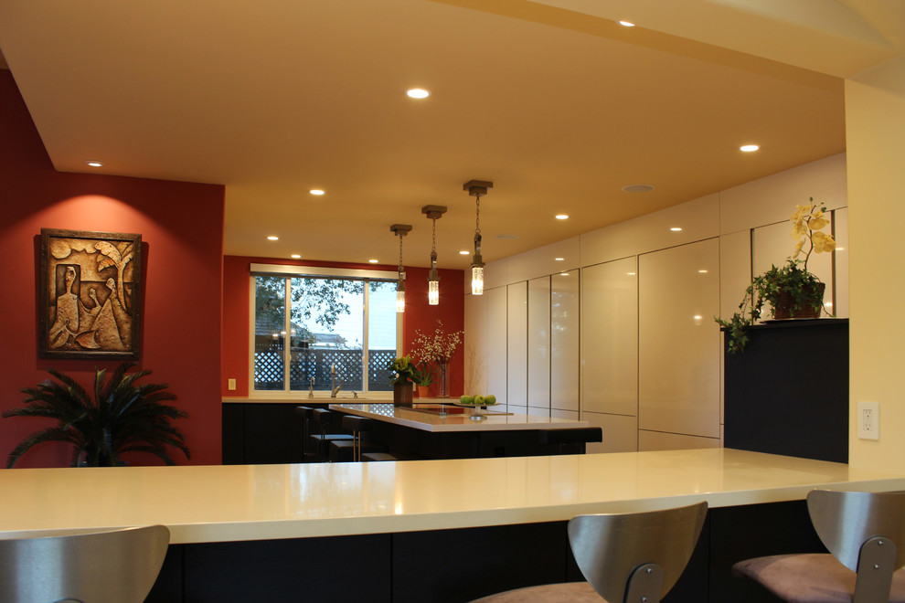 Photo of a contemporary u-shaped kitchen in San Francisco with an undermount sink, flat-panel cabinets, white cabinets, quartz benchtops, panelled appliances, light hardwood floors and multiple islands.