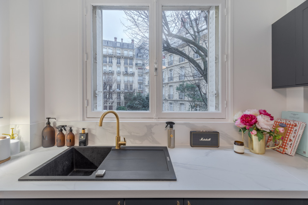 Mid-sized transitional u-shaped separate kitchen in Paris with a single-bowl sink, recessed-panel cabinets, black cabinets, laminate benchtops, white splashback, ceramic floors, grey floor and white benchtop.