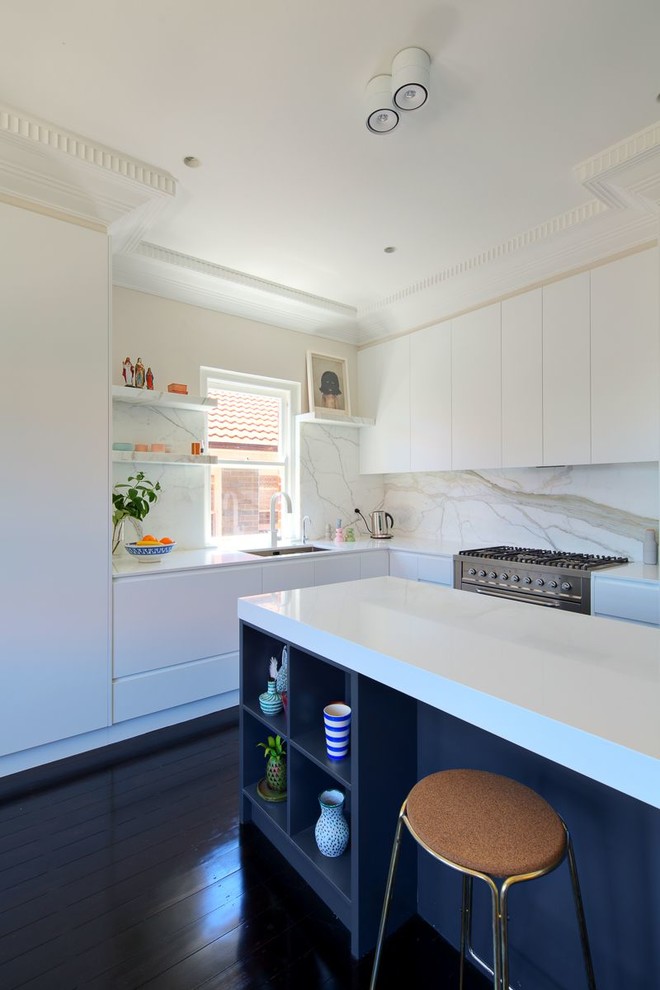 Mid-sized contemporary l-shaped open plan kitchen in Sydney with a drop-in sink, recessed-panel cabinets, white cabinets, quartz benchtops, stone slab splashback, white appliances, dark hardwood floors and with island.