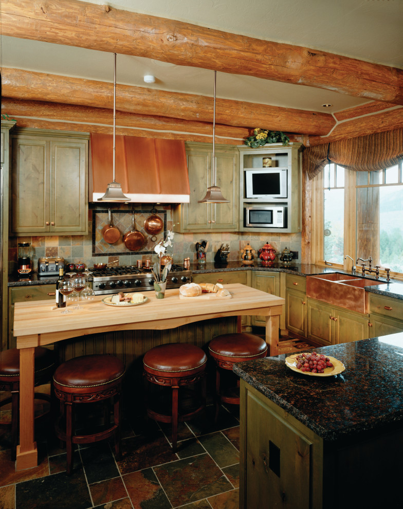 Photo of an expansive vintage kitchen/diner with a belfast sink, green cabinets, granite worktops, brick splashback, an island and black worktops.