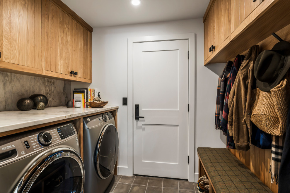 Mountain style galley gray floor utility room photo with flat-panel cabinets, medium tone wood cabinets, white walls, a side-by-side washer/dryer and gray countertops