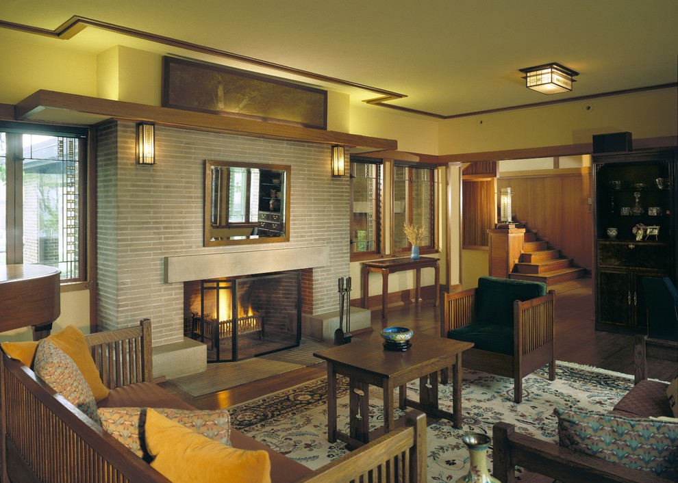 This is an example of a mid-sized arts and crafts formal open concept living room in Chicago with yellow walls, medium hardwood floors, a standard fireplace, a brick fireplace surround and no tv.