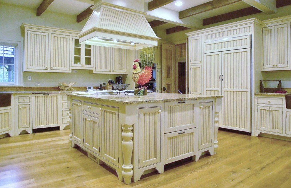 Inspiration for a large transitional u-shaped medium tone wood floor enclosed kitchen remodel with a farmhouse sink, beaded inset cabinets, white cabinets, granite countertops, brown backsplash, stone slab backsplash, paneled appliances and an island