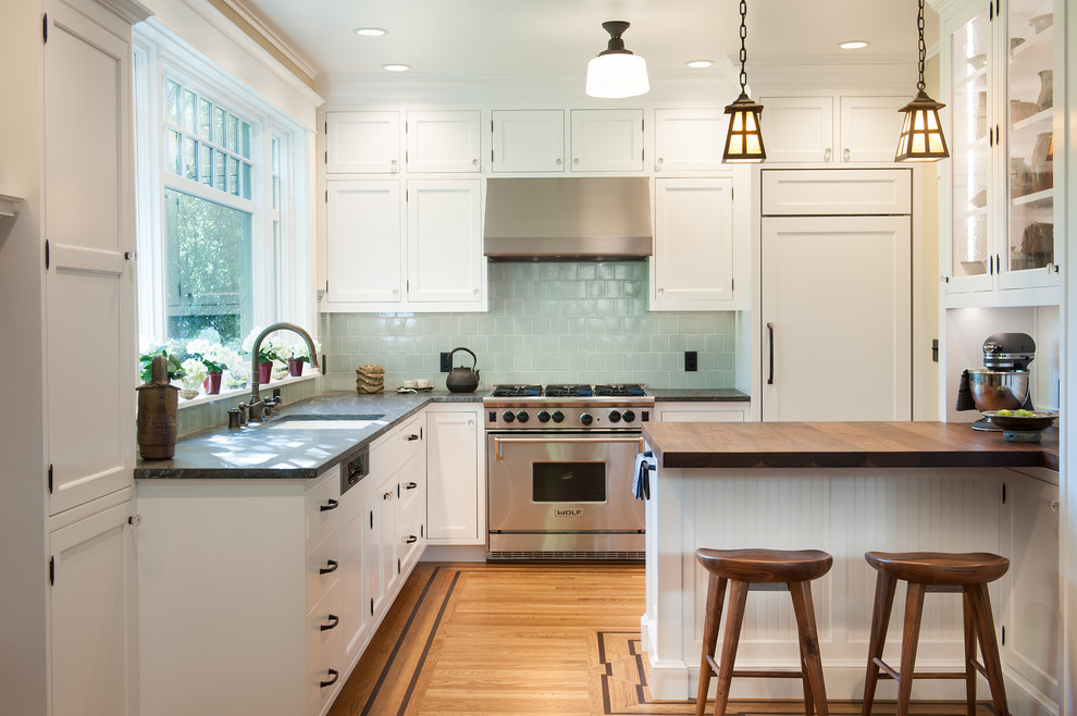 Small traditional l-shaped open plan kitchen in San Francisco with a single-bowl sink, beaded inset cabinets, white cabinets, soapstone benchtops, green splashback, ceramic splashback, white appliances, light hardwood floors and with island.