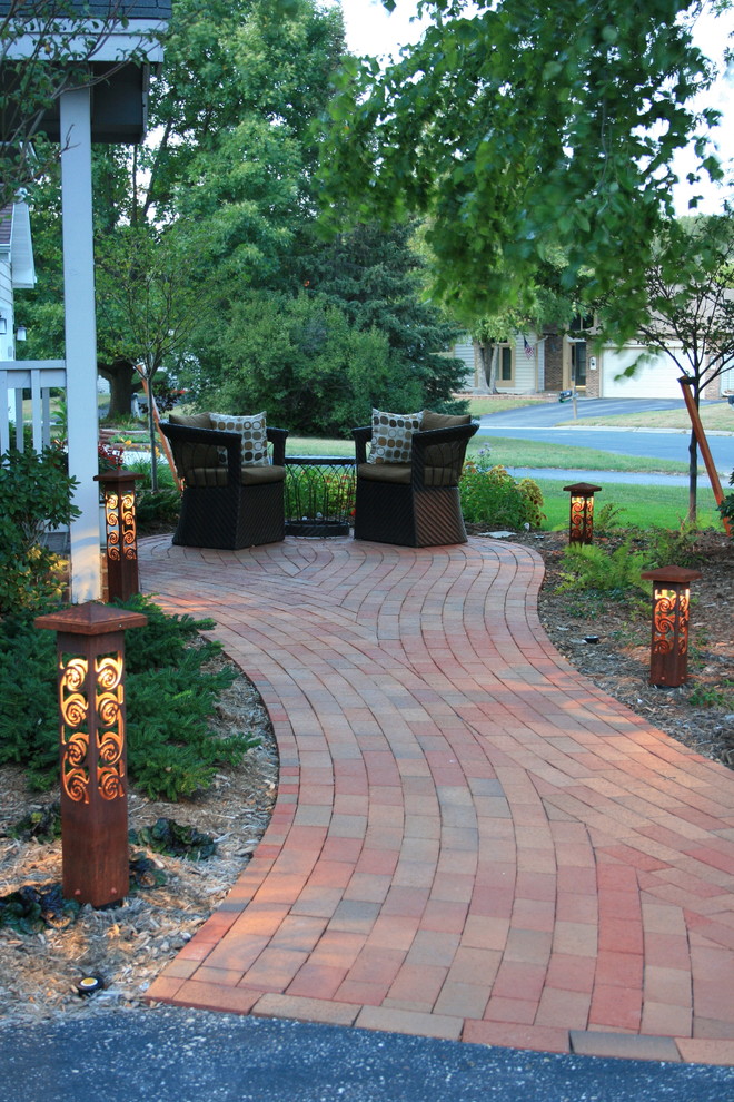 This is an example of a mid-sized traditional front yard partial sun driveway for summer in Minneapolis with brick pavers.