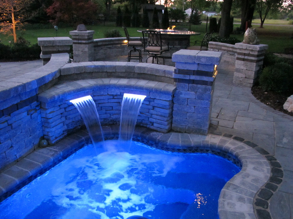 Example of a transitional backyard brick and custom-shaped hot tub design in Detroit