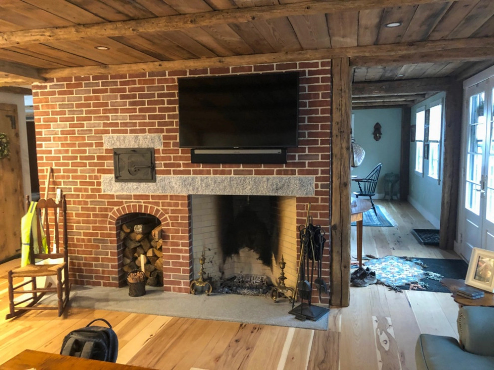 Uriges Wohnzimmer mit braunem Holzboden, Kaminumrandung aus Backstein und Holzdecke in Boston