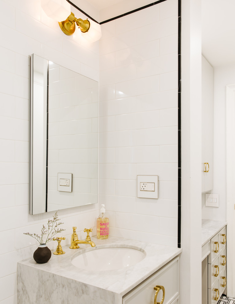 Photo of a mid-sized scandinavian 3/4 bathroom in Tampa with recessed-panel cabinets, white cabinets, an undermount tub, a shower/bathtub combo, a one-piece toilet, white tile, ceramic tile, white walls, ceramic floors, an undermount sink, marble benchtops, black floor and a shower curtain.