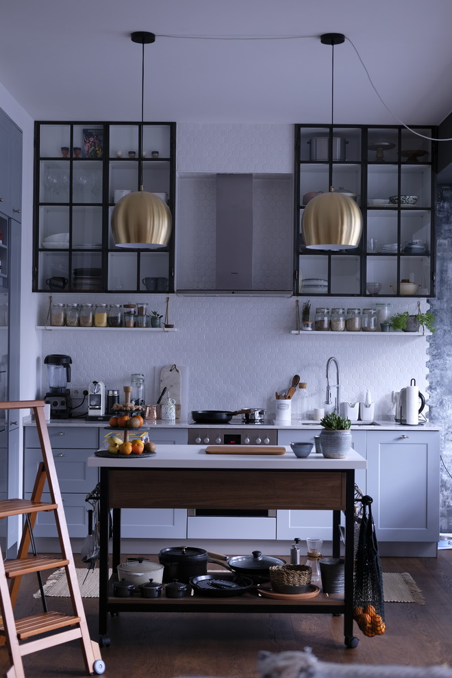 Design ideas for a small industrial galley kitchen in Berlin with an integrated sink, blue cabinets, white splashback, ceramic splashback, stainless steel appliances, dark hardwood floors, with island, brown floor, white benchtop and shaker cabinets.