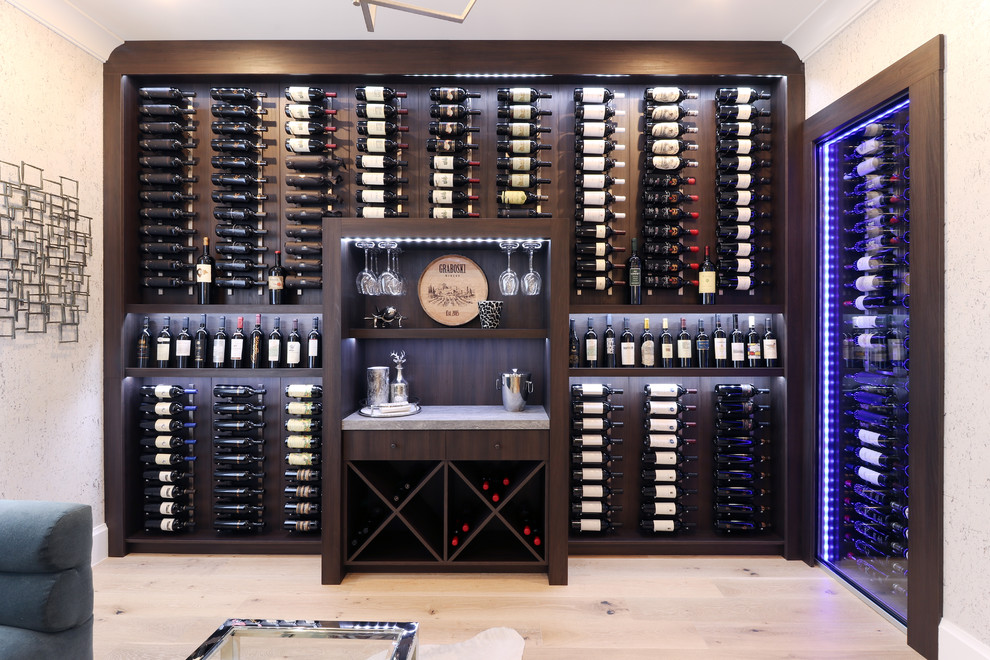 Photo of a contemporary wine cellar in Miami with light hardwood floors and display racks.