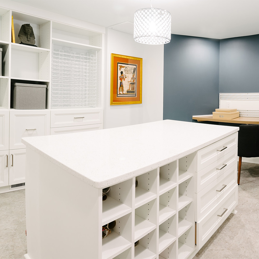 This is an example of a mid-sized transitional craft room in Detroit with white walls, vinyl floors, a built-in desk and brown floor.