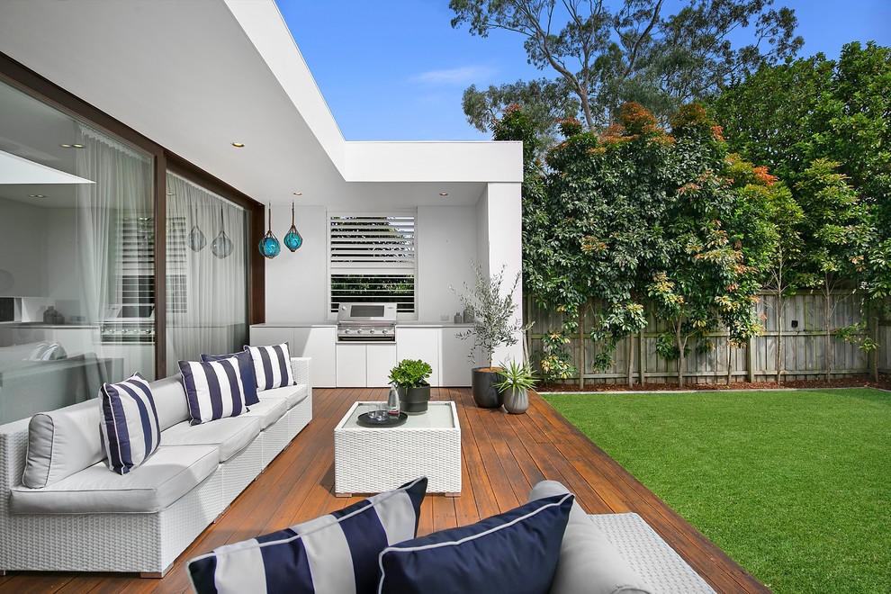 Photo of a mid-sized transitional backyard deck in Sydney with an outdoor kitchen and a roof extension.