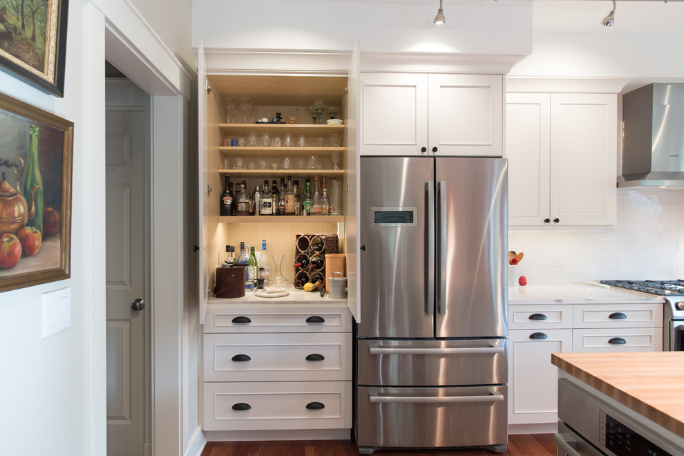 Example of a mid-sized transitional l-shaped medium tone wood floor and brown floor eat-in kitchen design in Seattle with an undermount sink, recessed-panel cabinets, white cabinets, quartz countertops, white backsplash, ceramic backsplash, stainless steel appliances, an island and white countertops