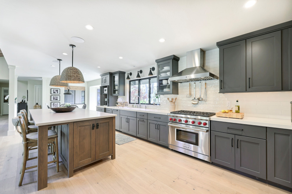 Open concept kitchen - mid-sized transitional l-shaped laminate floor open concept kitchen idea with a double-bowl sink, flat-panel cabinets, gray cabinets, quartz countertops, white backsplash, ceramic backsplash, stainless steel appliances, an island and white countertops