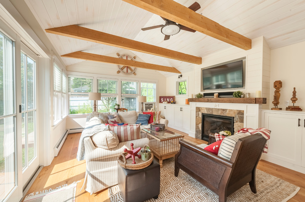 Inspiration for a country family room in Boston with a standard fireplace, a stone fireplace surround, a wall-mounted tv, beige walls, medium hardwood floors and brown floor.