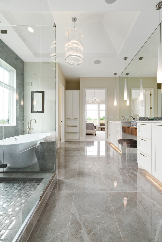 Design ideas for a mid-sized transitional master bathroom in Kansas City with white cabinets, a freestanding tub, a corner shower, gray tile, beige walls, an undermount sink, grey floor, a hinged shower door, white benchtops and raised-panel cabinets.