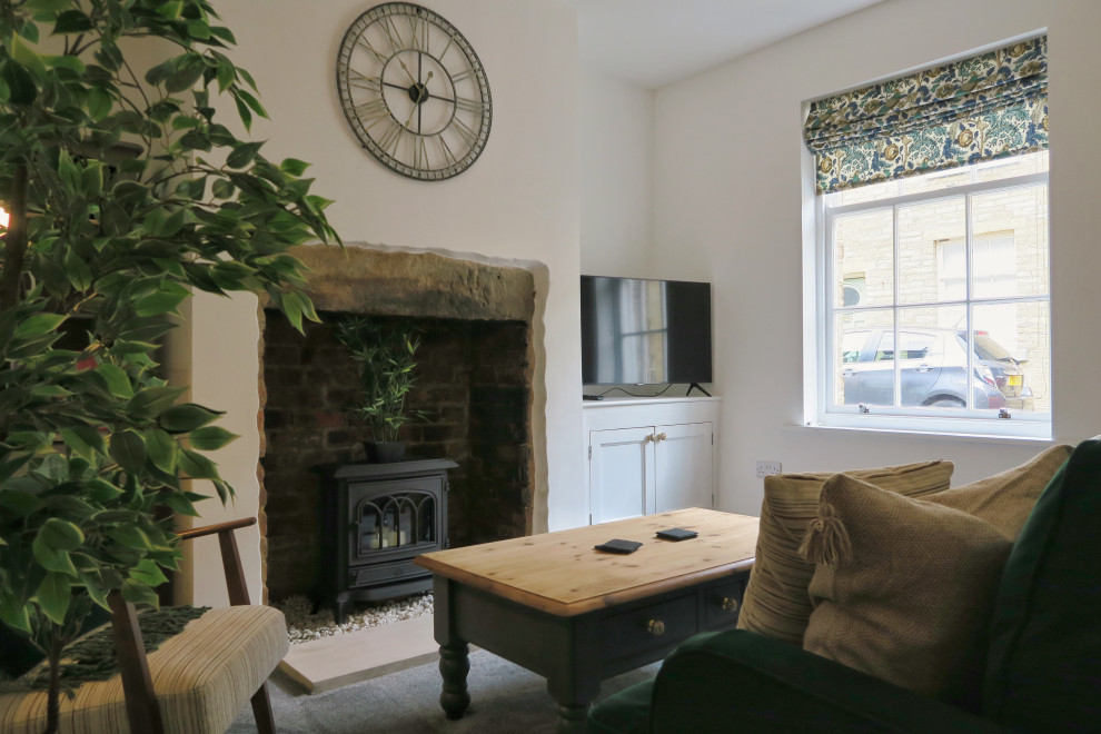Foto di un piccolo soggiorno vittoriano chiuso con pareti bianche, moquette, cornice del camino in pietra, TV autoportante e pavimento grigio